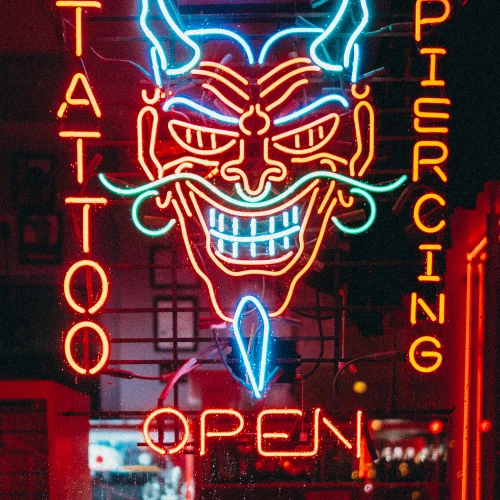 Vibrant neon tattoo and piercing shop sign—small businesses can boost visibility with affordable web design.