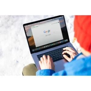 Design & Development – Simple Sites A laptop displaying a Google search homepage, used outdoors in a snowy environment, highlighting accessibility and efficiency.